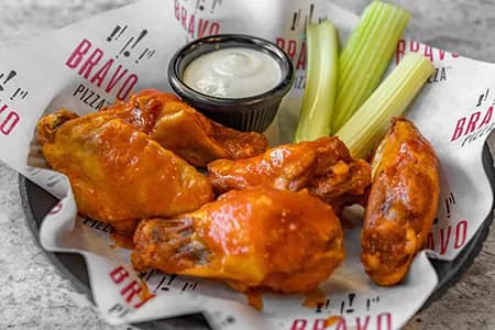 Boneless buffalo wings with blue cheese and celery on a metal tray