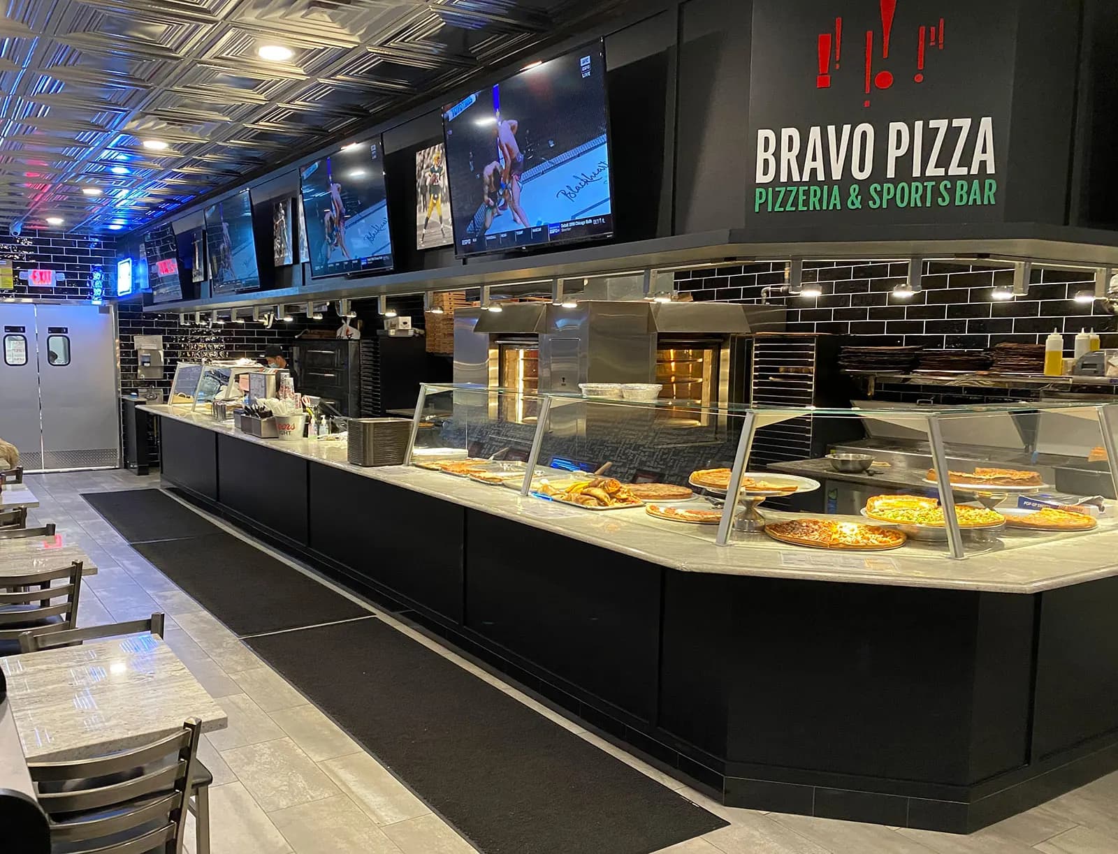 Bravo Pizza storefront at night, with string lights over the outdoor tables