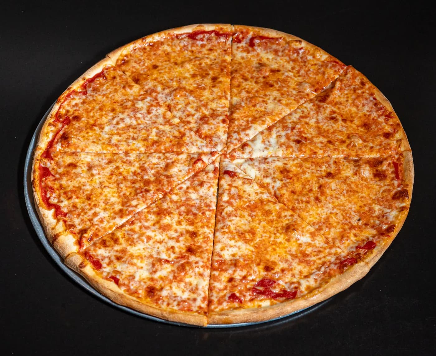 Large regular pizza pie with melted cheese and a golden crust on a metal tray
