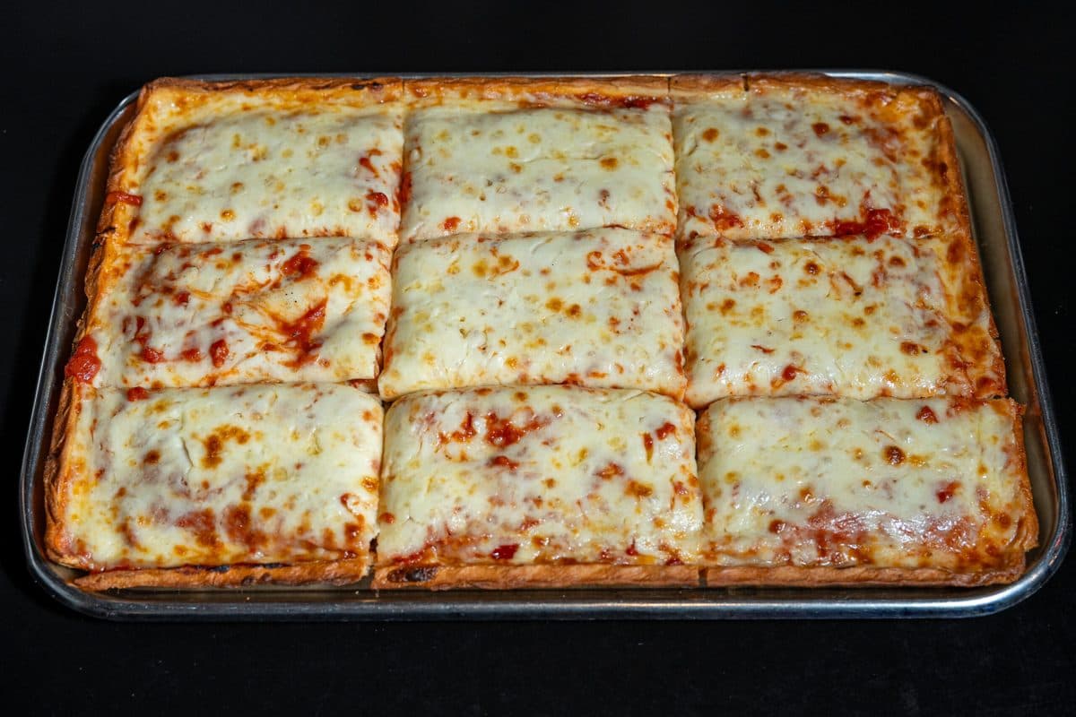 Square Sicilian pie with tomato sauce, melted mozzarella, and basil